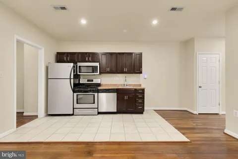 a kitchen with granite countertop a refrigerator and a stove top oven