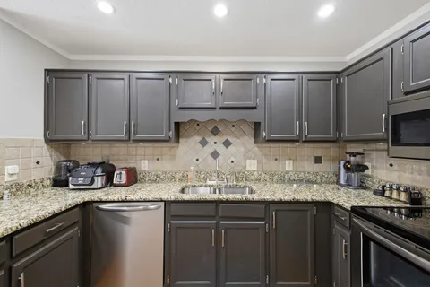 a kitchen with stainless steel appliances granite countertop a sink stove and cabinets