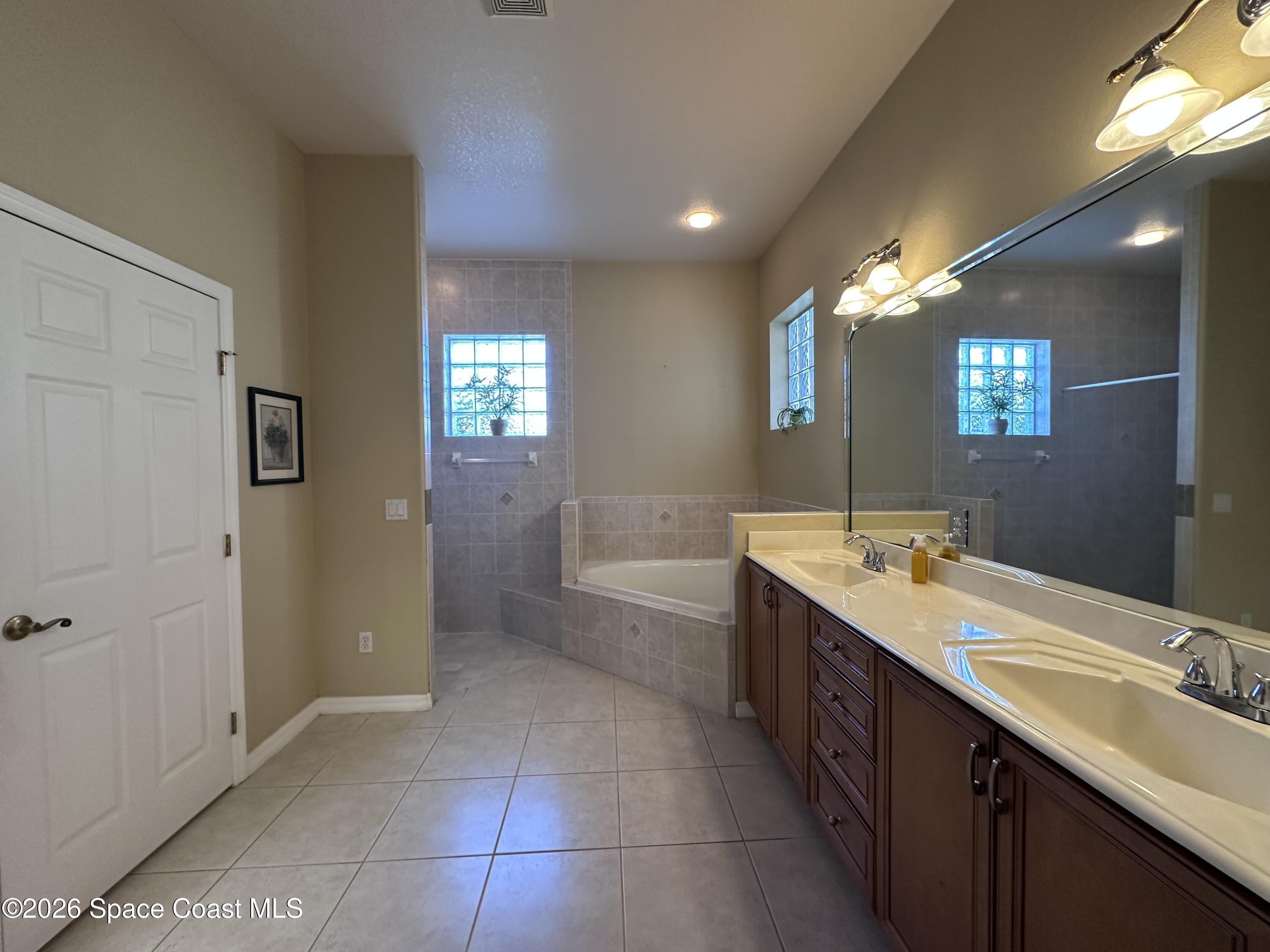 883 Spring Oak Drive Melbourne, FL 32901 - Photo 24 of 45 a bathroom with a double vanity sink a large mirror and a shower