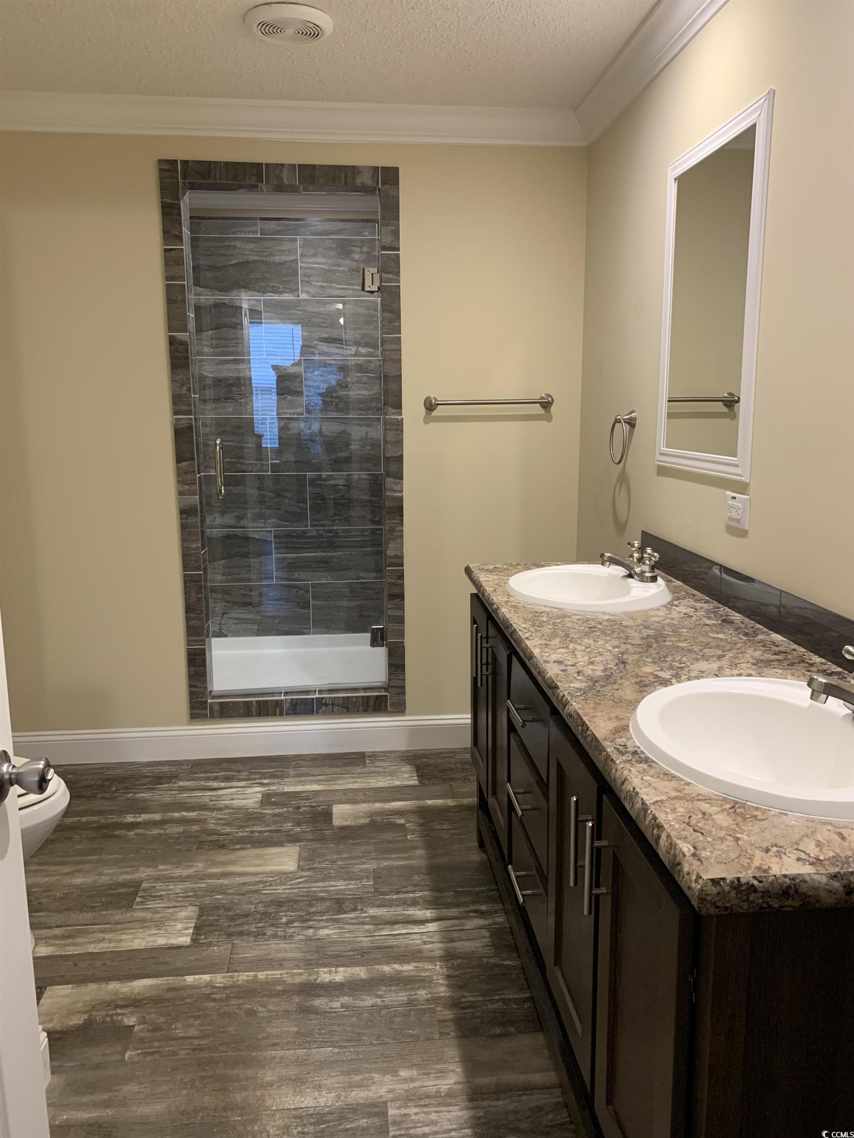 1651 Perry Circle Myrtle Beach, SC 29577 - Photo 20 of 32 Bathroom featuring double vanity, a shower stall, a textured ceiling, dark wood-type flooring, and ornamental molding