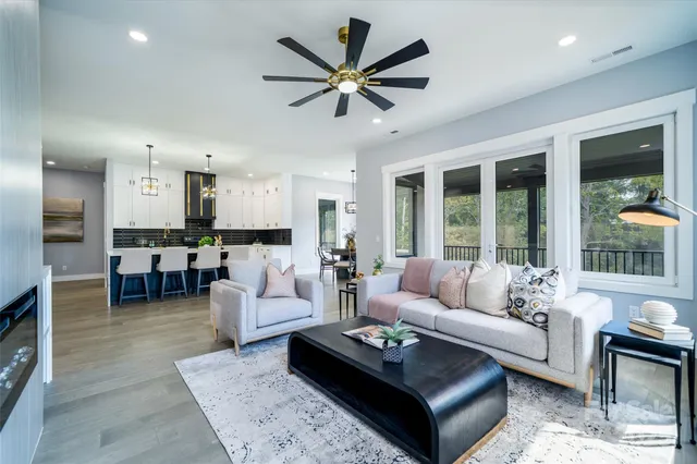 a living room with furniture kitchen view and a large window