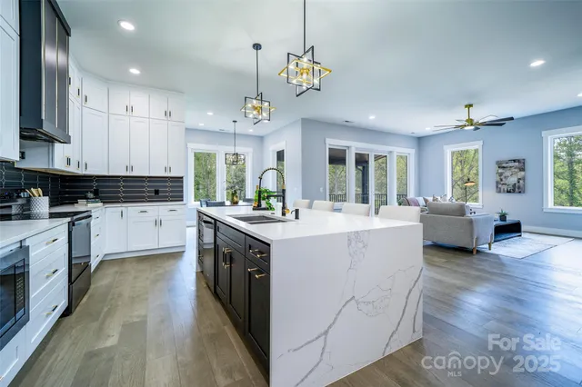 a kitchen with kitchen island granite countertop a sink cabinets and wooden floor