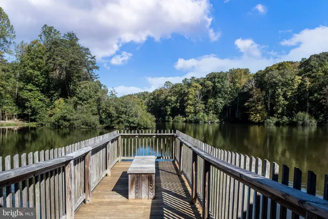 a patio with tables and chairs under an umbrella with a small yard