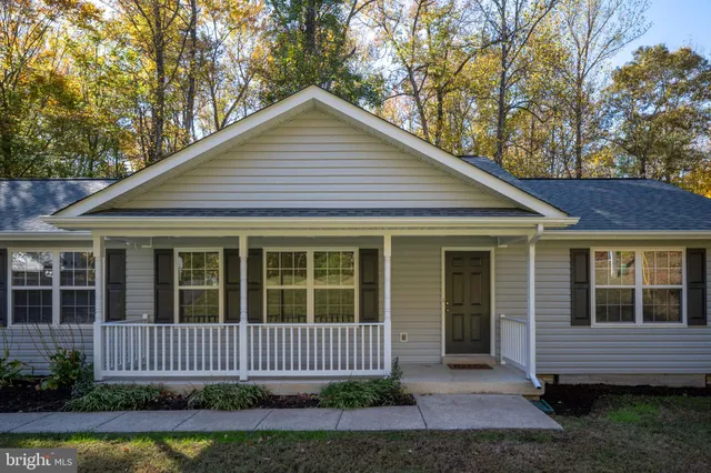 a view of a house with a yard chairs and a tree