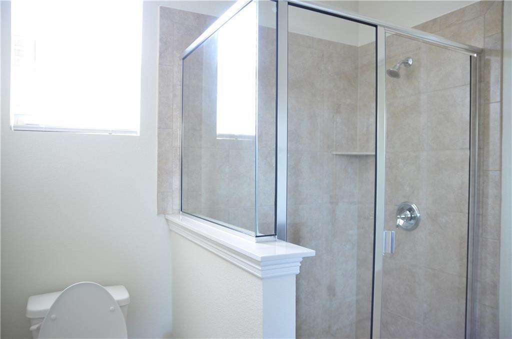 14403 McCoy Loop Austin, TX 78717 - Photo 14 of 29 A well-lit bathroom with a glass-enclosed shower and tiled walls.
