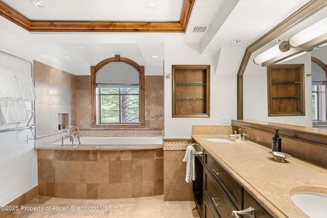 a en suite bathroom with a granite countertop tub a sink and a large window