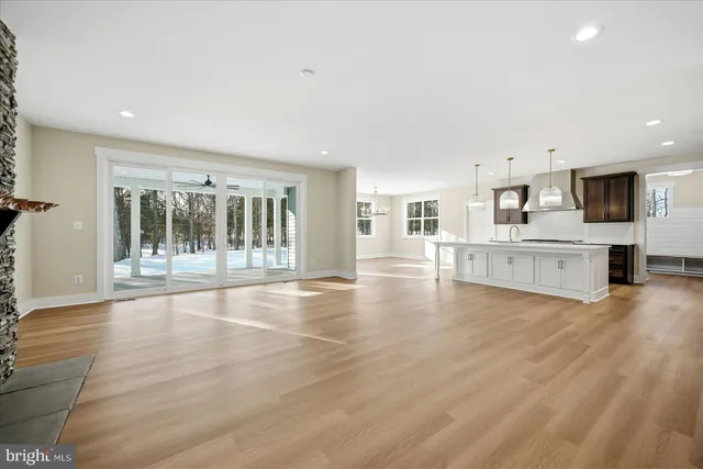 a view of an empty room with kitchen and a window