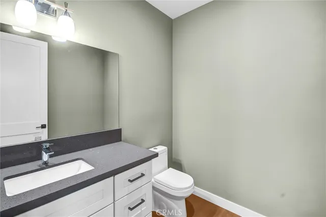 a bathroom with a granite countertop sink a toilet and a mirror