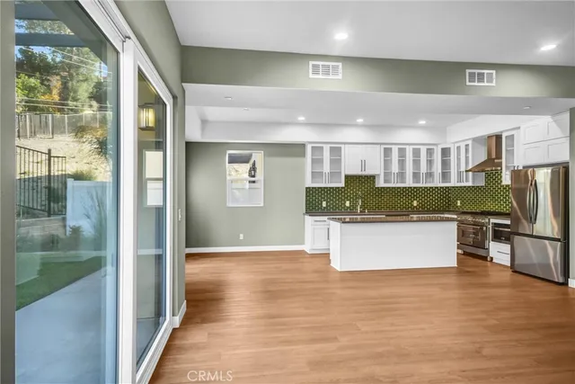 a kitchen with stainless steel appliances kitchen island a large counter top and a wooden floors