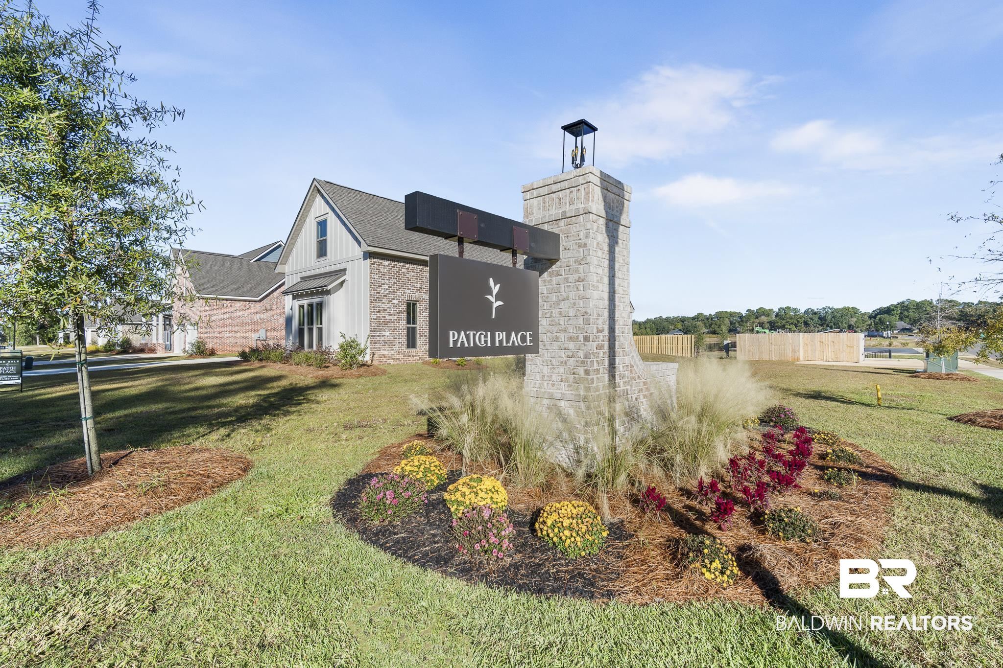 27398 Patch Place Loop Daphne, AL 36526 - Photo 4 of 5 Stone monument sign with integrated lighting, surrounded by manicured landscaping with decorative plantings