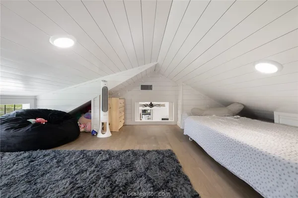 a large bedroom with a bed and wooden floor