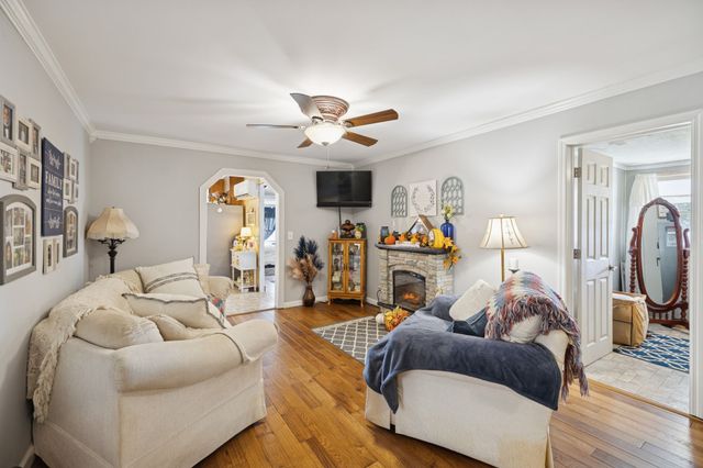 a living room with furniture a flat screen tv and a ceiling fan