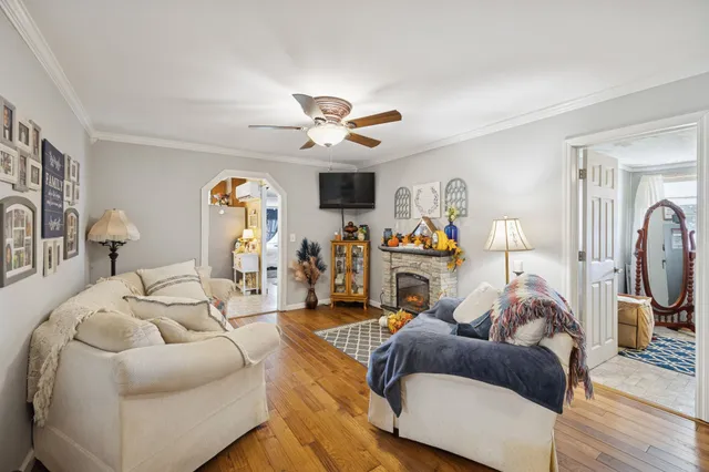 a living room with furniture a flat screen tv and a ceiling fan