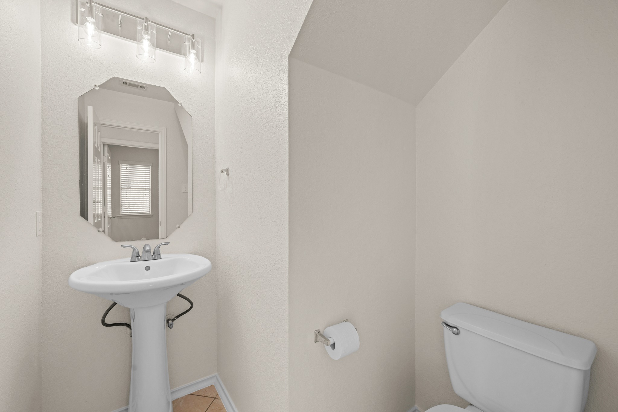 3410 Flowstone Lane Round Rock, TX 78681 - Photo 14 of 38 Convenient downstairs half bath with pedestal sink, large mirror, and ample lighting—perfect for guests.