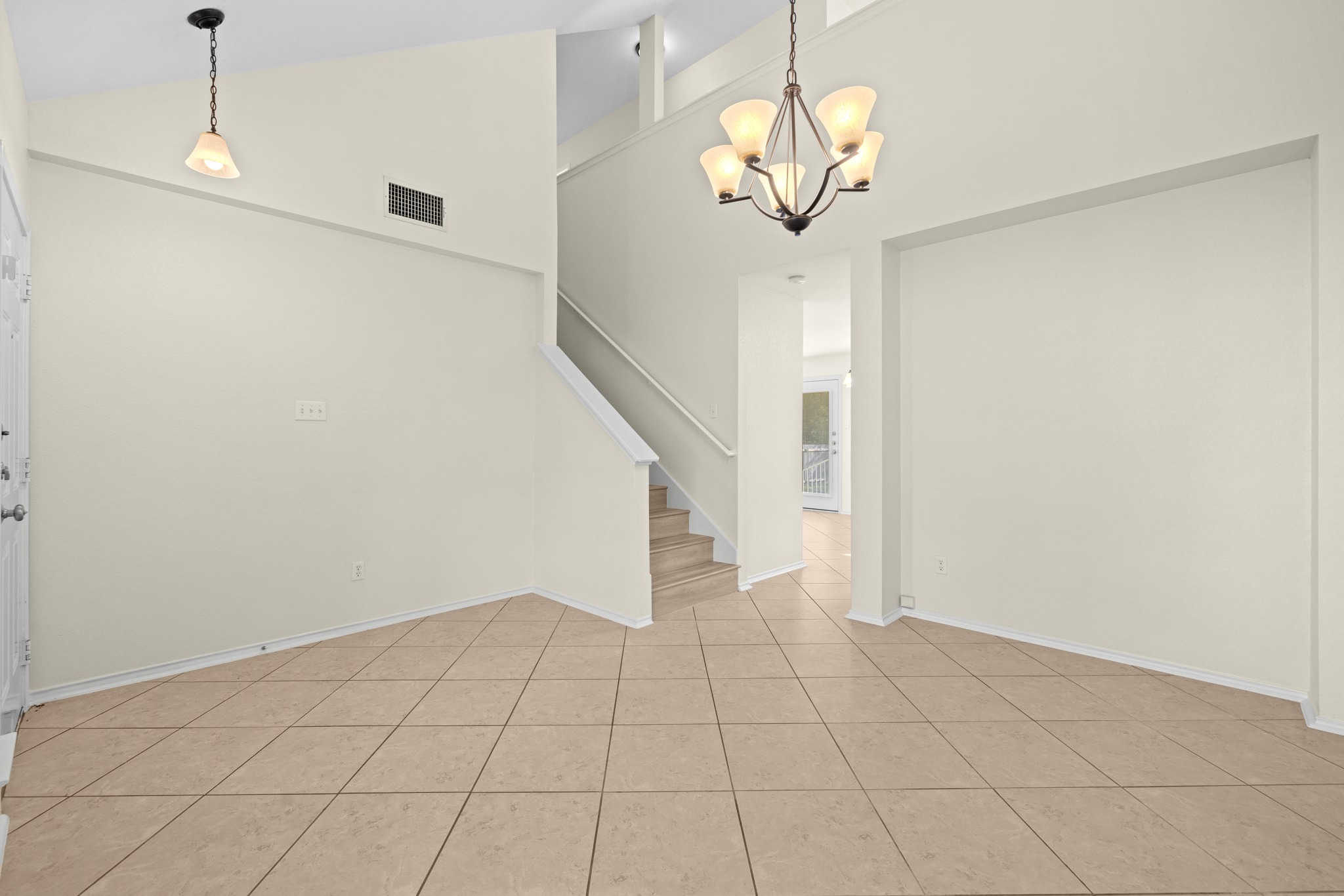 3410 Flowstone Lane Round Rock, TX 78681 - Photo 15 of 38 Open living space with high ceilings and tiled flooring, conveniently located near the staircase and entry. A modern chandelier adds a stylish touch.