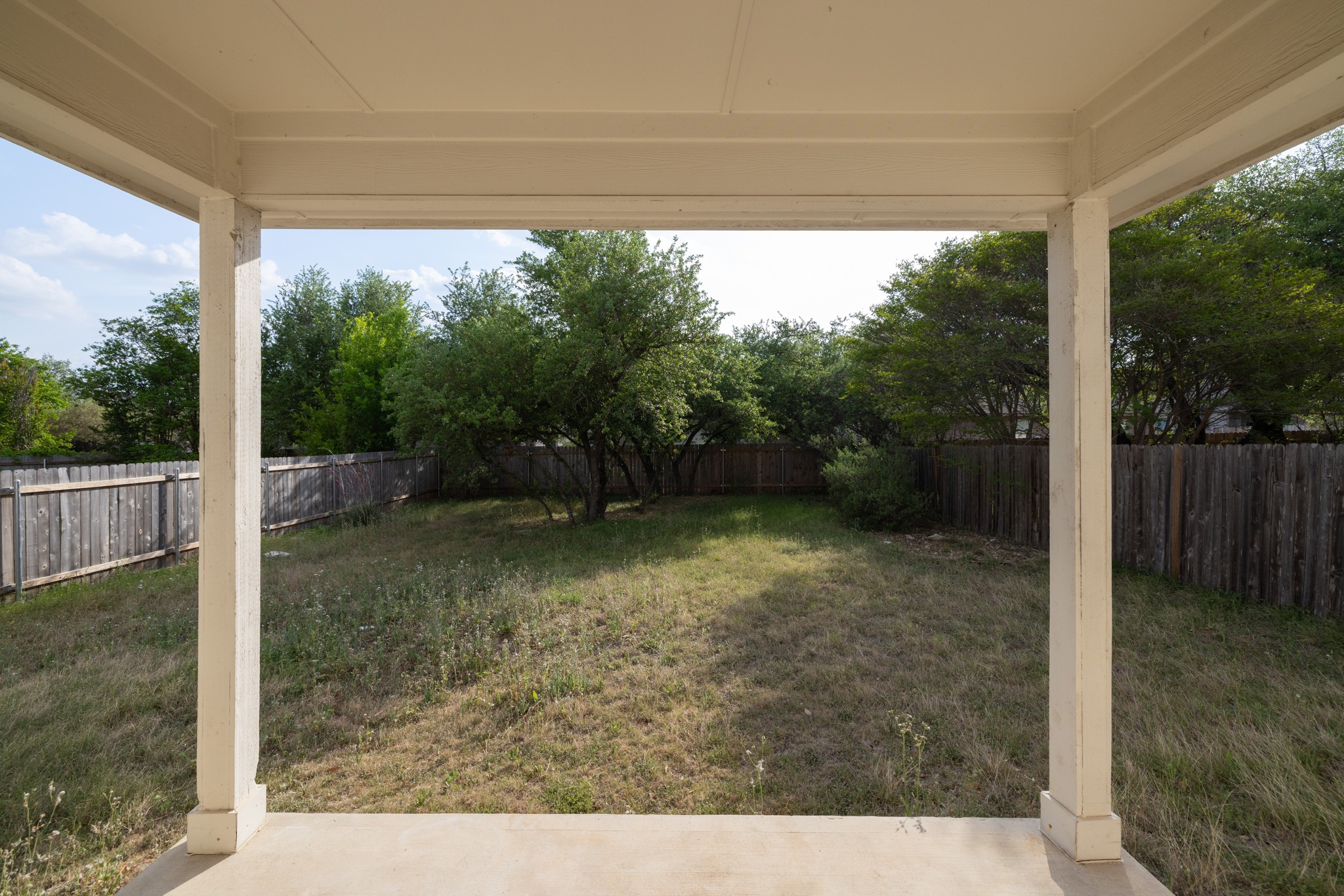 3410 Flowstone Lane Round Rock, TX 78681 - Photo 26 of 38 View from the covered patio overlooking a large, private backyard with mature trees providing shade. Ideal space for relaxing, gardening, or outdoor activities.