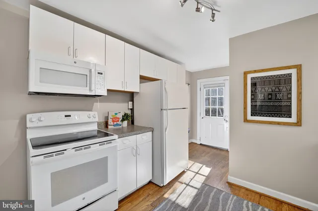 a kitchen with white cabinets and white appliances