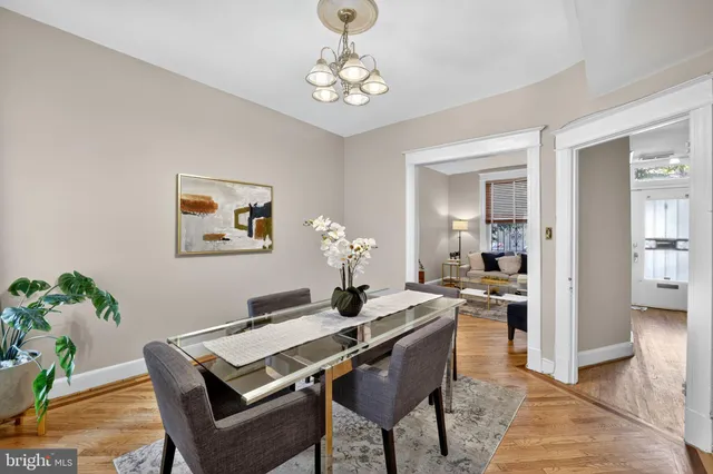 a dining room with wooden floor a chandelier a wooden table and chairs