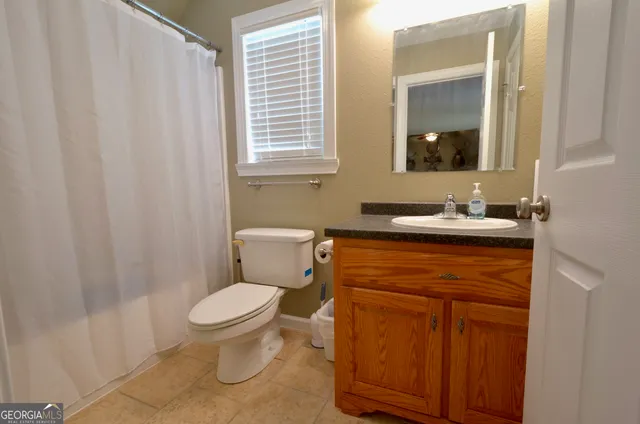 a bathroom with a granite countertop toilet sink and mirror