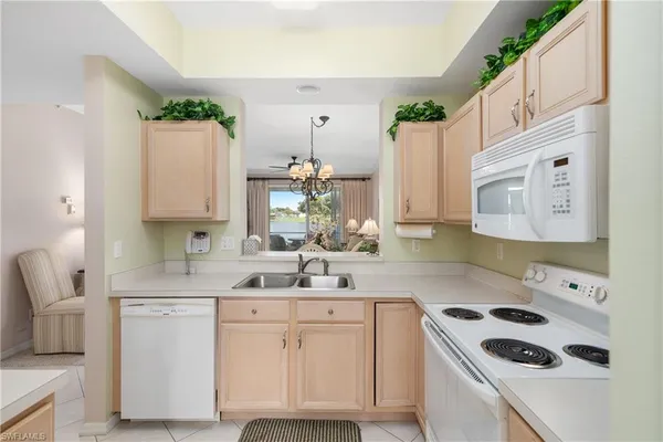 a kitchen with cabinets appliances a sink and a potted plant
