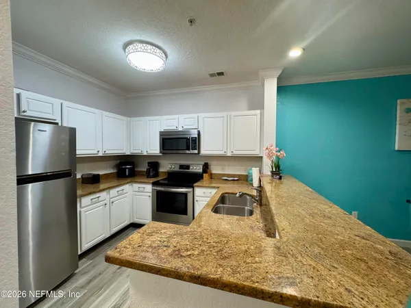 a kitchen with a refrigerator sink and wooden cabinets