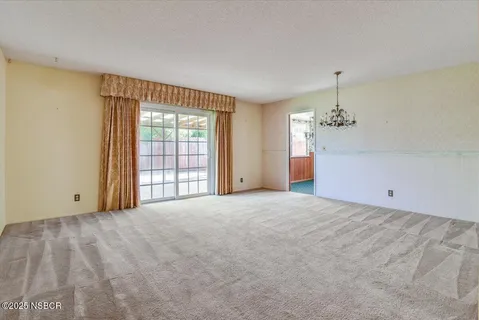 a view of a livingroom with a chandelier fan and windows