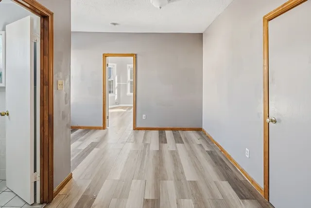 a view of a hallway with wooden floor and a bathroom
