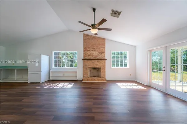 a view of an empty room with a window and wooden floor