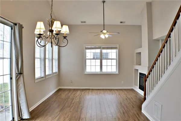 an empty room with wooden floor chandelier and windows