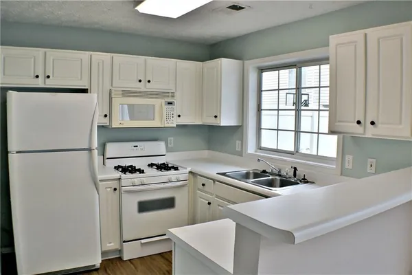 a kitchen with white cabinets and white appliances