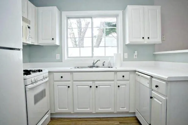 a kitchen with granite countertop white cabinets and white appliances