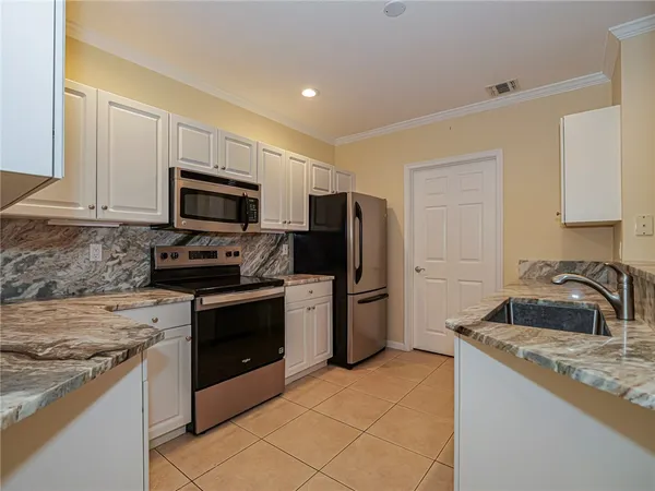 a kitchen with granite countertop white cabinets stainless steel appliances and a sink