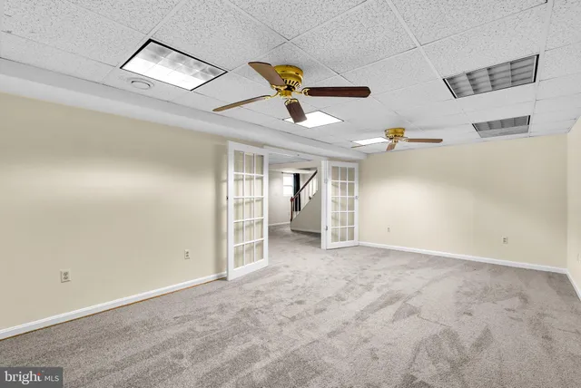 an empty room with ceiling fan and windows