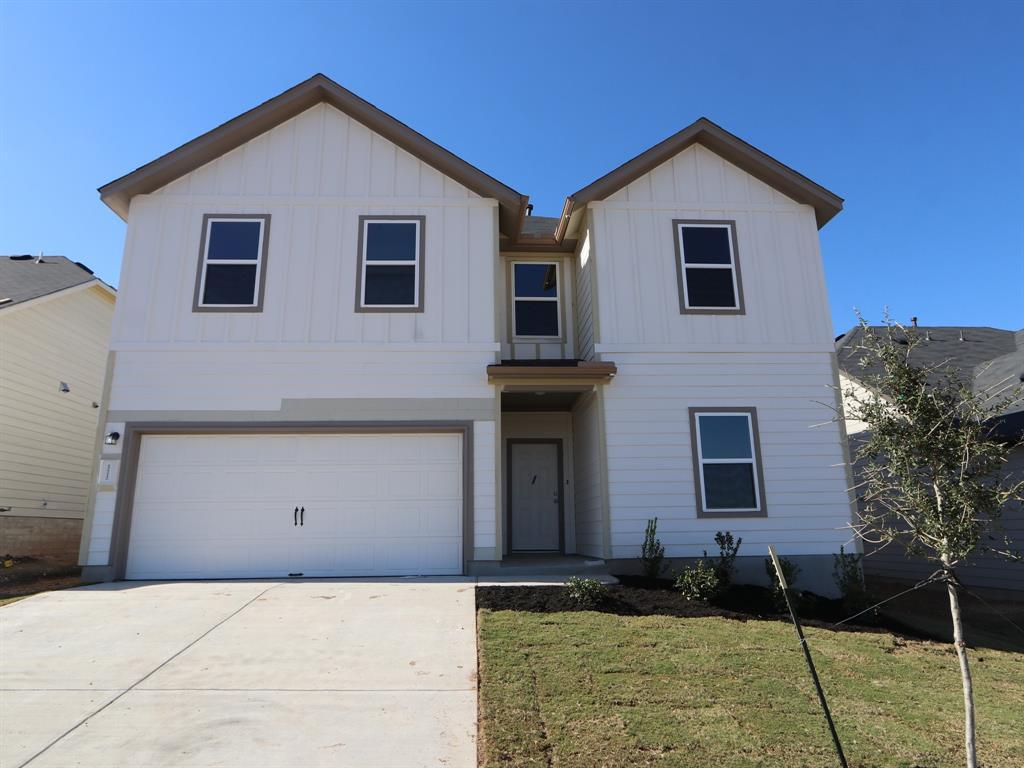 View of front of house with board and batten siding, an attached garage, concrete driveway, and a front yard