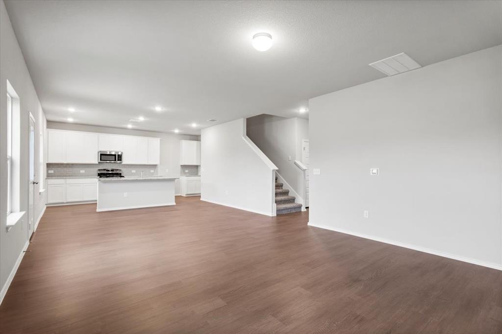 12212 Dillon Fls Drive Austin, TX 78747 - Photo 5 of 40 Unfurnished living room featuring dark wood-style flooring, recessed lighting, and stairway