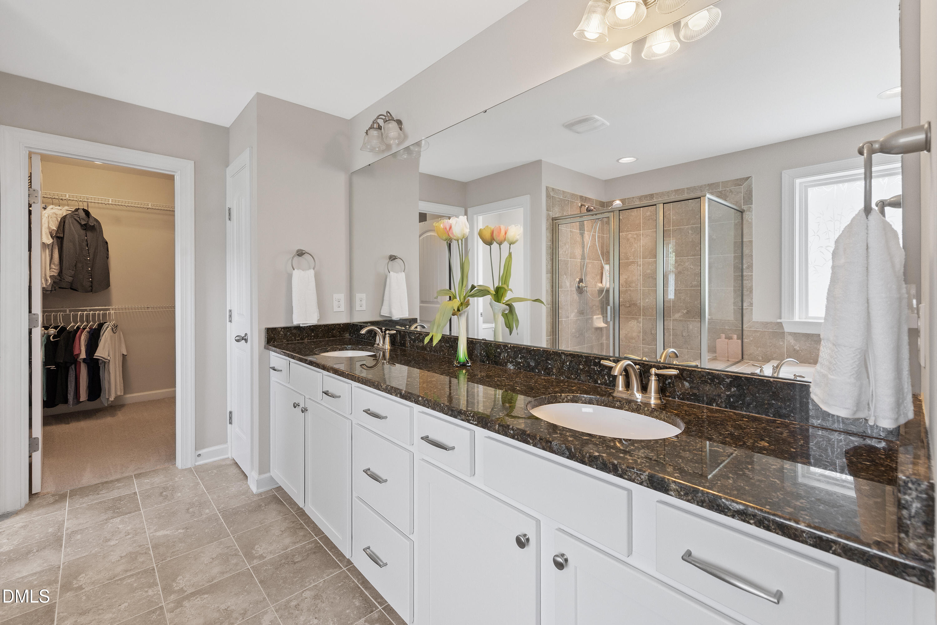 8059 Gilano Drive Raleigh, NC 27603 - Photo 28 of 43 a bathroom with double vanity sinks a large mirror and a shower