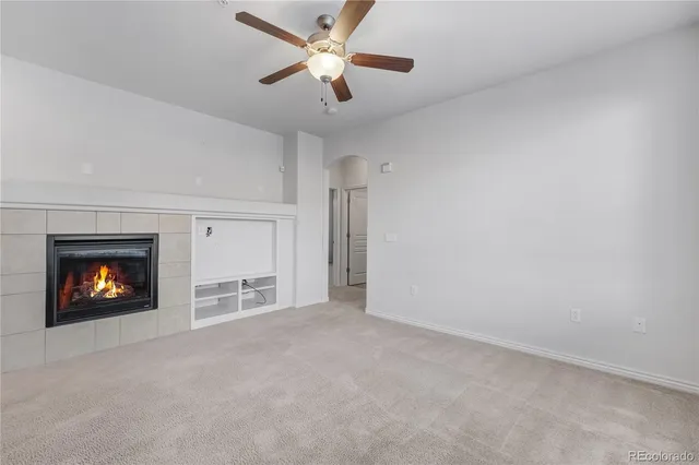 an empty room with a fireplace and a ceiling fan