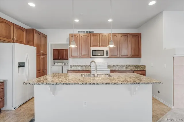 a kitchen with kitchen island granite countertop a sink stove and refrigerator