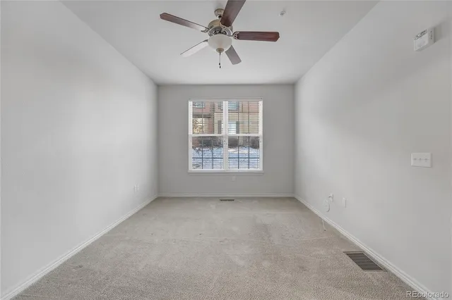an empty room with a window and a ceiling fan