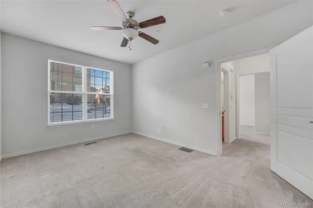 an empty room with windows and fan