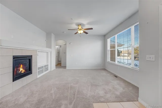 a view of an empty room with chandelier fan and fire place