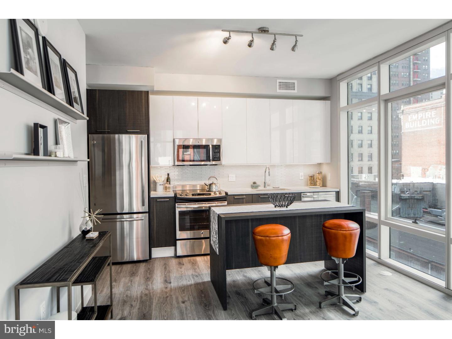 a kitchen with stainless steel appliances granite countertop a stove a refrigerator a sink a dining table and chairs