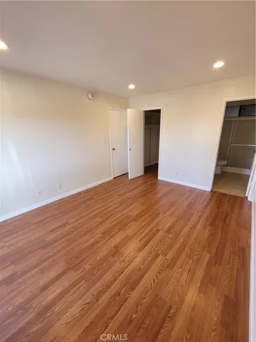 a view of an empty room with wooden floor and a sink