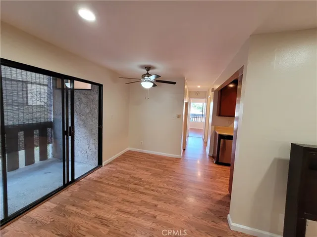 a view of a hallway with wooden floor and a kitchen space