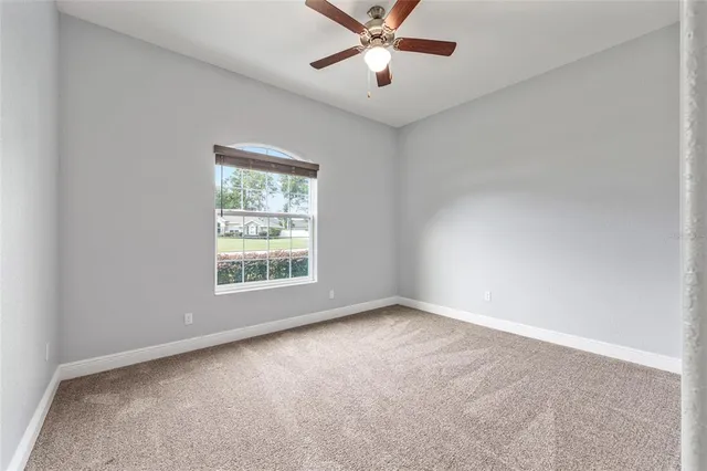 an empty room with a window and a fan