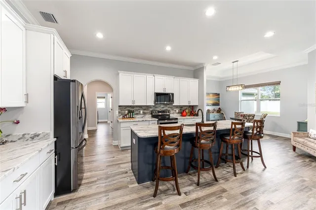 a open dining room with stainless steel appliances kitchen island granite countertop a dining table chairs and granite counter tops
