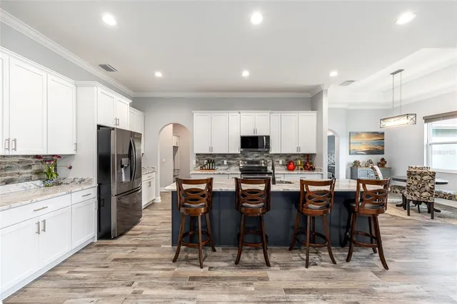 a kitchen with stainless steel appliances kitchen island granite countertop a table chairs refrigerator and microwave