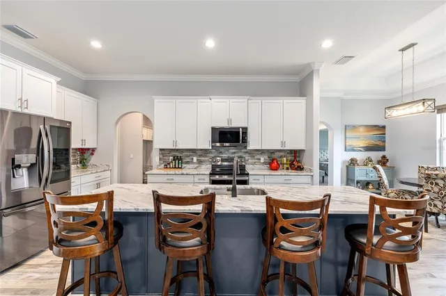 a kitchen with stainless steel appliances a dining table chairs refrigerator and microwave