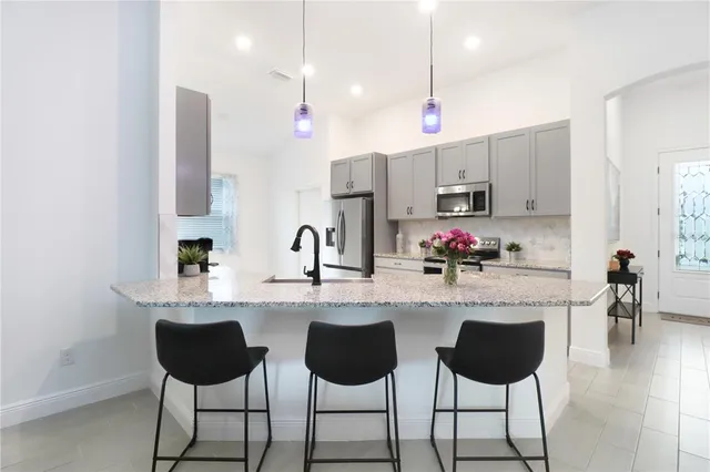 a kitchen with stainless steel appliances kitchen island granite countertop a stove a sink and a refrigerator