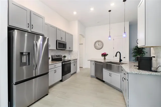 a kitchen with stainless steel appliances granite countertop a refrigerator a sink dishwasher a stove and a refrigerator